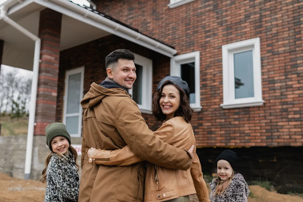 Familia abrazada delante de su casa